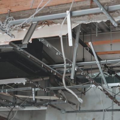 天井崩落した室内の金属フレームと配線の写真