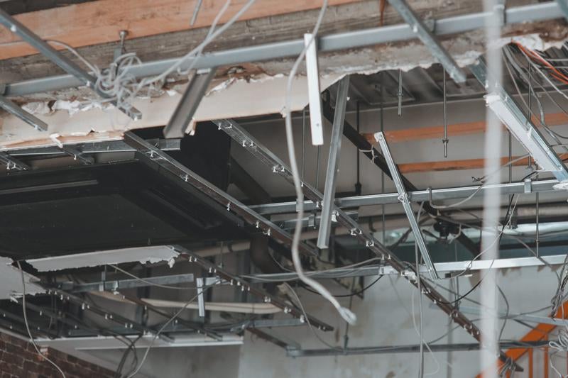 天井崩落した室内の金属フレームと配線の写真