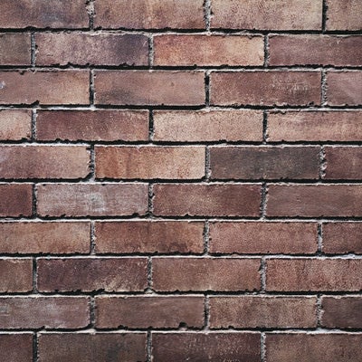 煉瓦のかけが目立つ色褪せたレンガ壁（テクスチャー）の写真