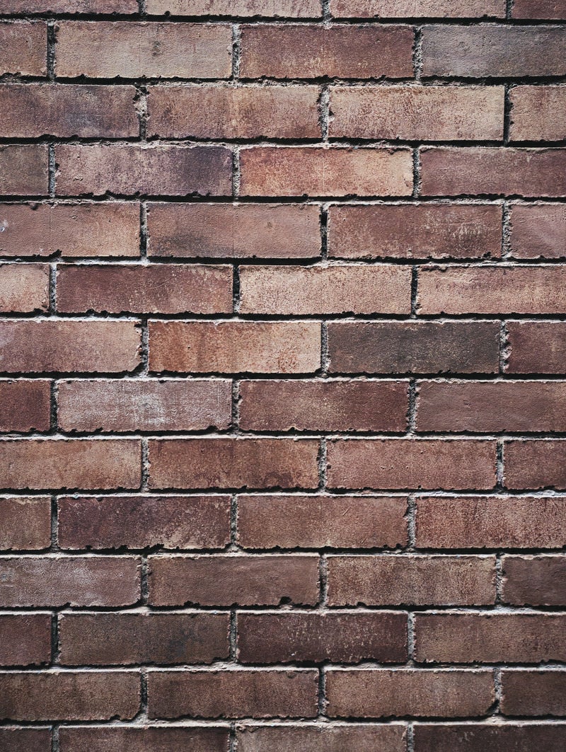 「煉瓦のかけが目立つ色褪せたレンガ壁（テクスチャー）」の写真