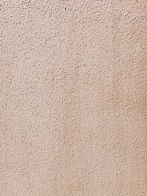 茶色くシミが浮かぶモルタル壁（テクスチャ）の写真