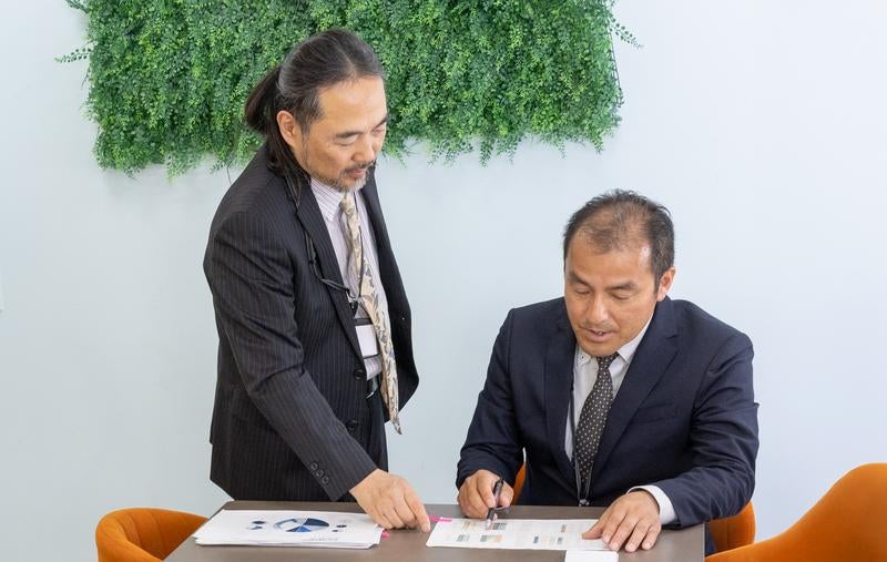 印刷した資料を見ながら指摘する男性社員の写真