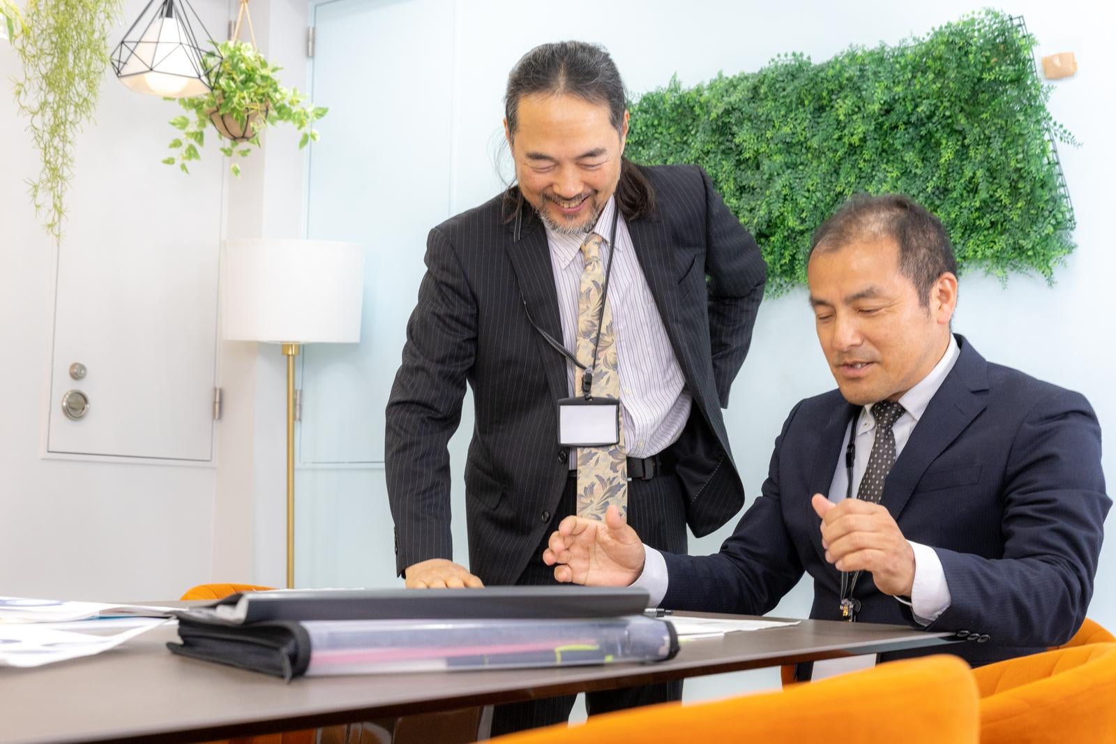 「会議後に和気あいあいと談話する管理職の男性」の写真［モデル：平野 高木桂一］