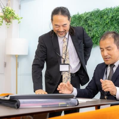 会議後に和気あいあいと談話する管理職の男性の写真