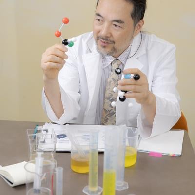 分子モデルを持った白衣の教授の写真