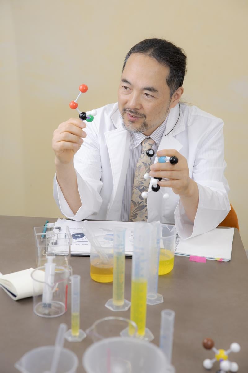 分子モデルを持った白衣の教授の写真