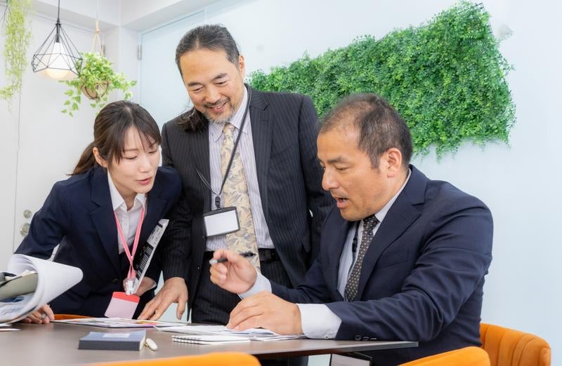 転職したばかりの中途採用に紙で説明する女性と役員の様子の写真