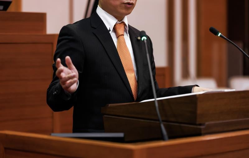 演壇して手振りで語る議員の姿の写真