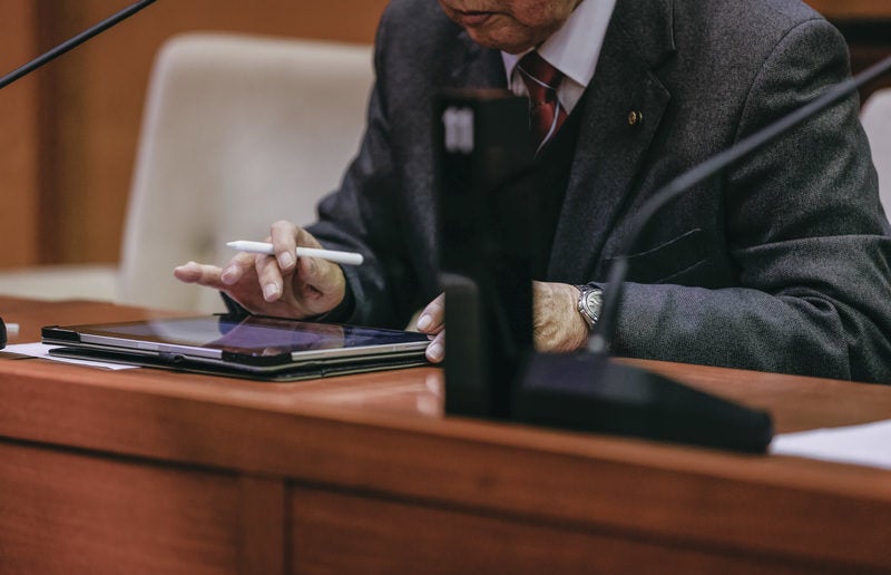 おぼつかないながらもタブレットを使う津山市議会の議員の写真