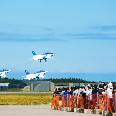 飛び立つブルーインパルス3機と観客の写真