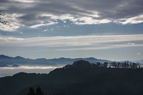 ややかすんで見える葛山城（かつらやまじょう）跡と奥に広がる雲海と連なる山々の写真