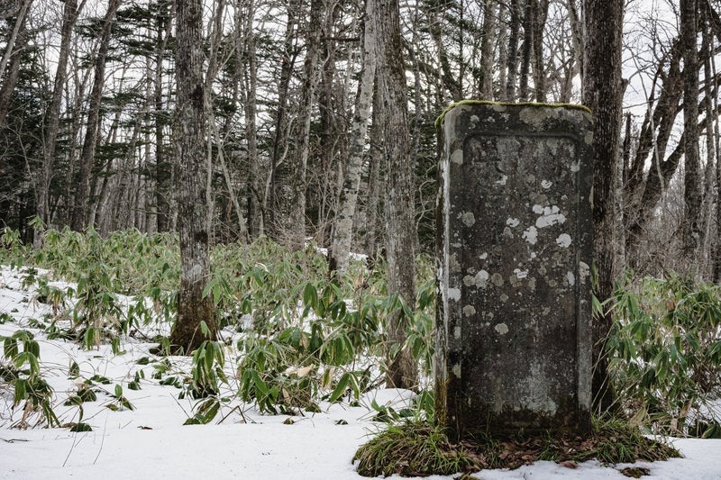 雪の残る戸隠神社奥社参道脇に建つ高妻山神鏡碑の写真