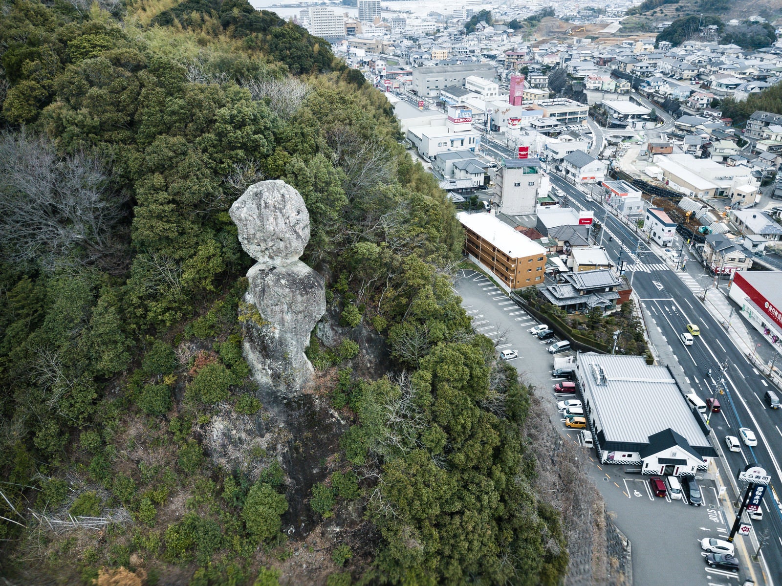 「車通りが多い街中にある落ちそうな巨岩（鯖くさらかし岩）」の写真