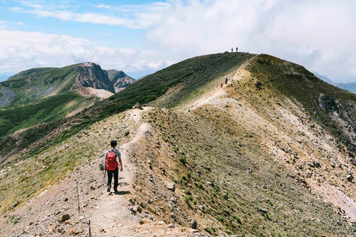 十勝岳から上ホロカメットク山へ歩く登山者の写真