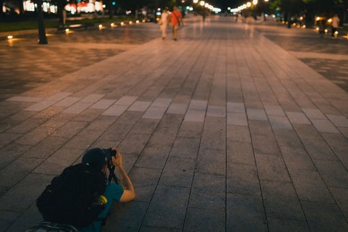 東京駅「丸の内駅前広場」を寝そべり撮影する外国人の写真