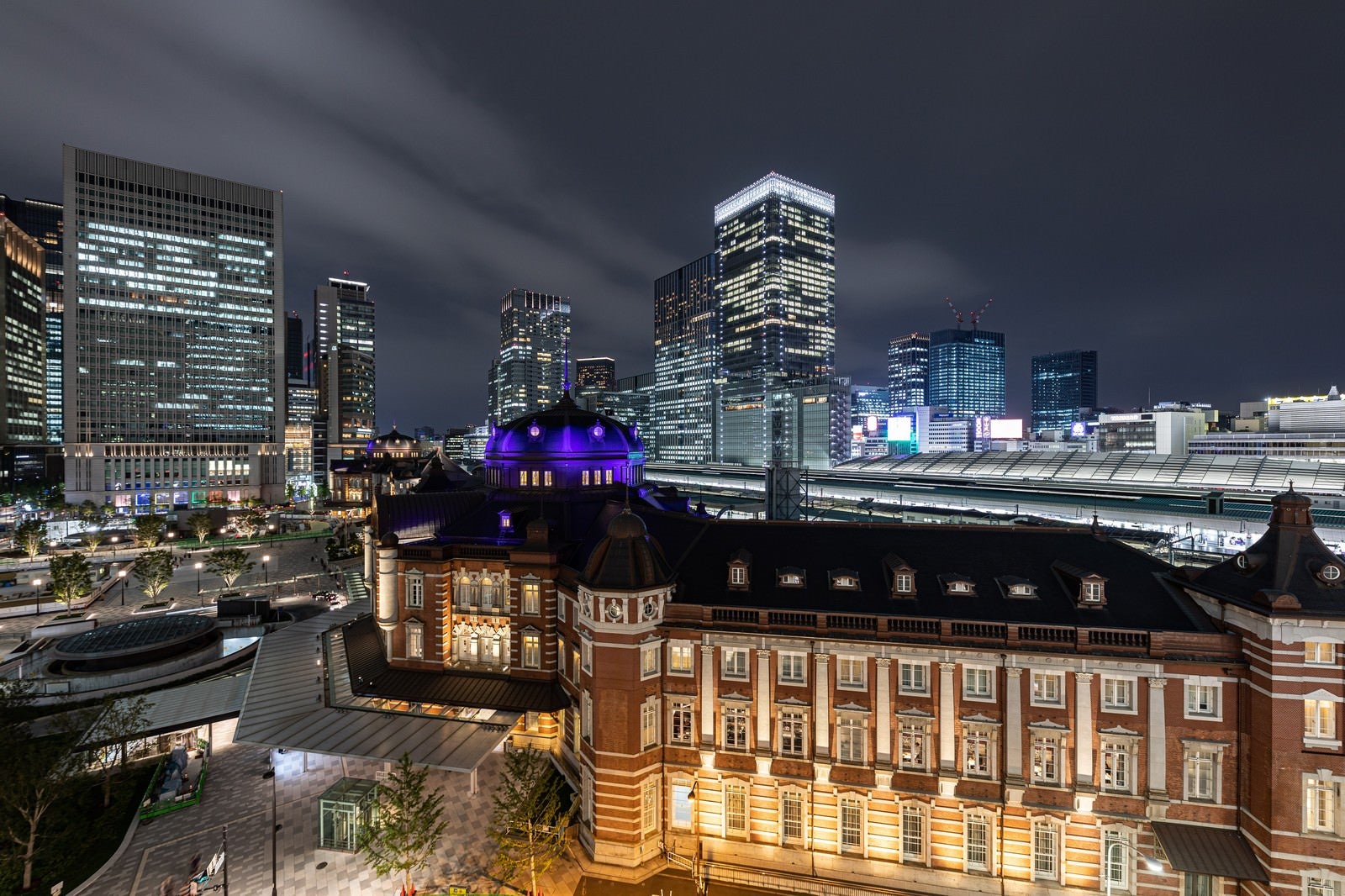 「ライトアップされた東京駅越しに見る丸の内ビル群」の写真