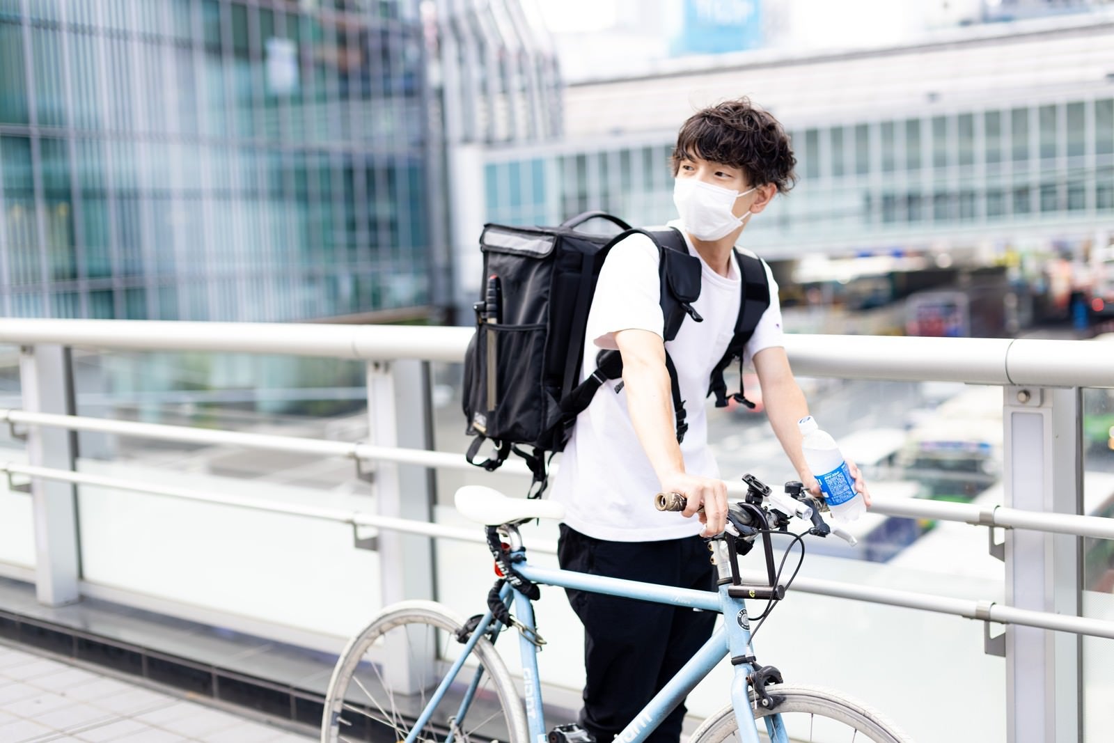 「配達を終えて自転車をおして歩く男性配達員」の写真［モデル：TSURUTAMA］