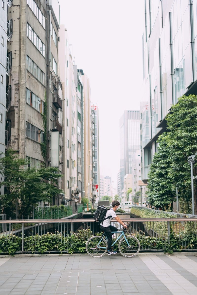 「自転車に乗って配達地に向かうフードデリバリー」の写真［モデル：TSURUTAMA］