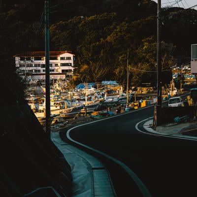 カーブを描く道路の先に広がる三重県答志島の朝焼けと港の写真
