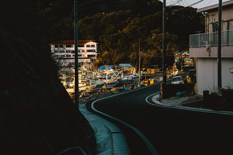 カーブを描く道路の先に広がる三重県答志島の朝焼けと港の写真