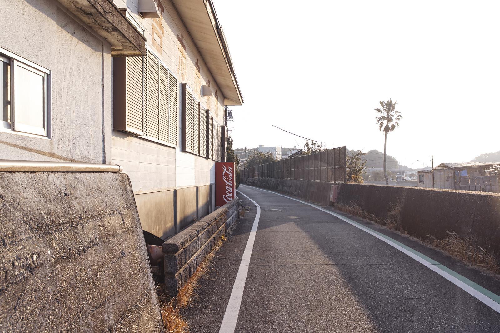 「港町のカーブ道と赤い自販機のある日常風景」の写真