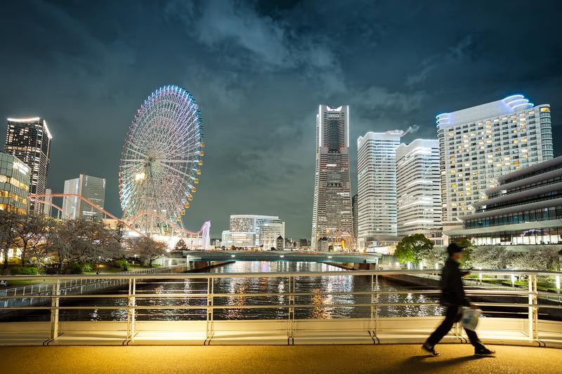 夜の横浜みなとみらいと歩道橋を歩く人影の写真