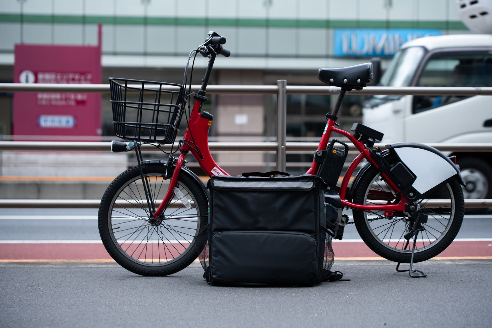 「路上に止めたフードデリバリーのバッグと自転車」の写真