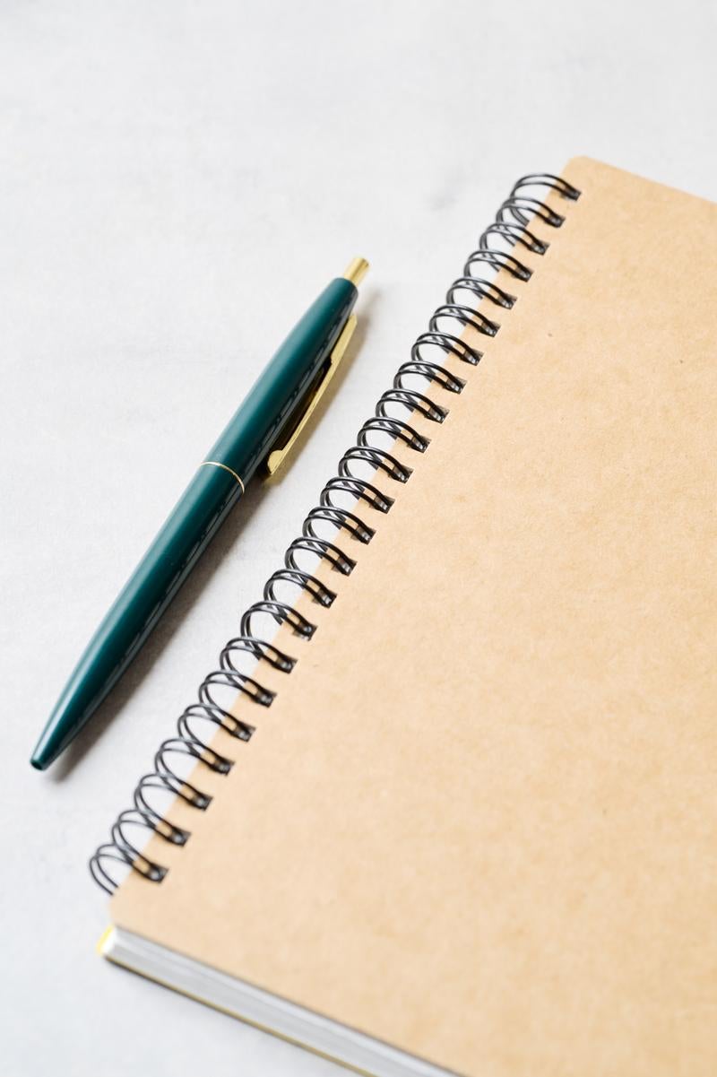 シンプルなデスクアイテムのノートとペンの写真