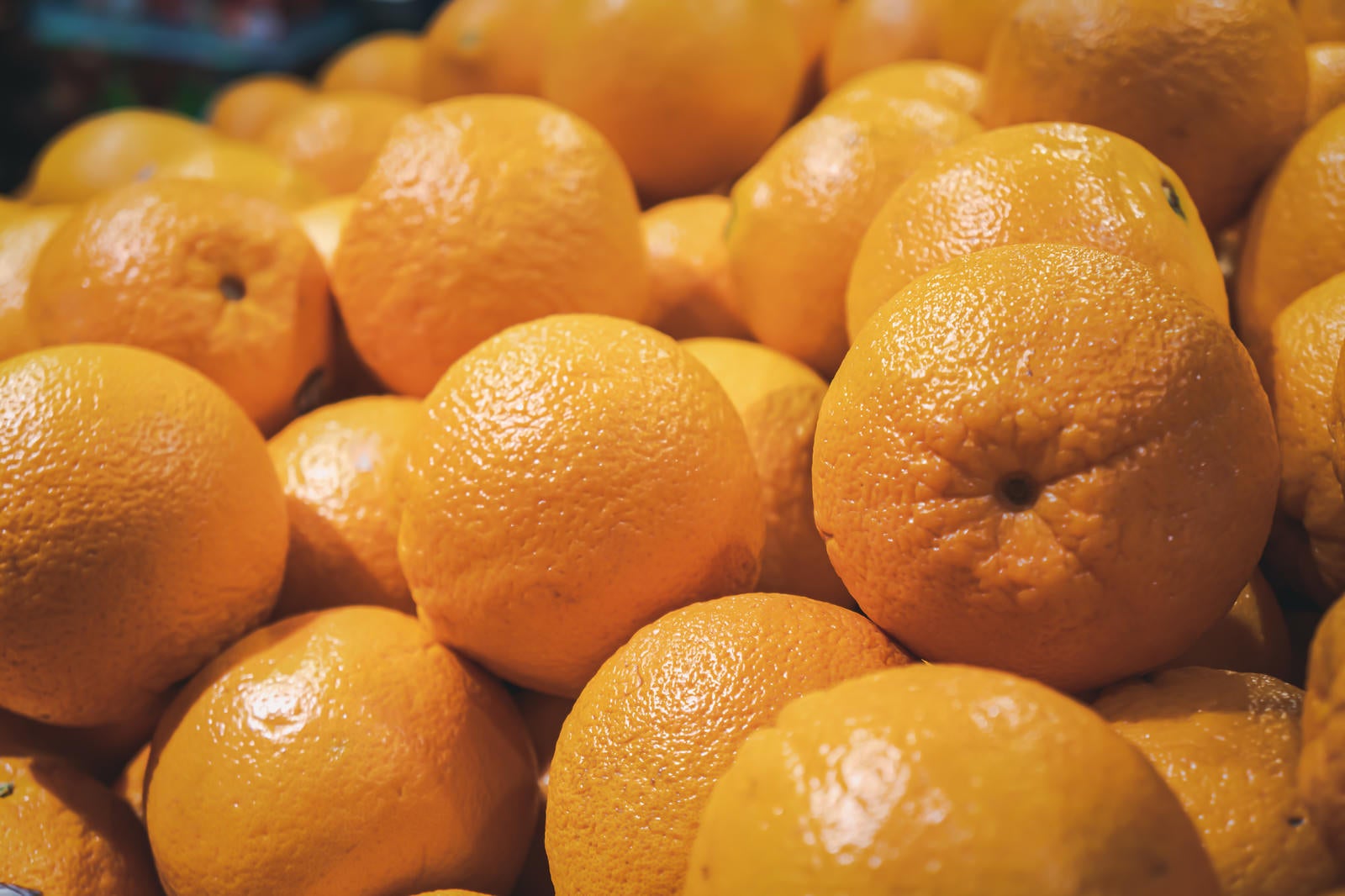 「スーパーの果物コーナーに積まれた大量のオレンジ」の写真