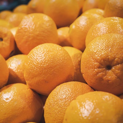 スーパーの果物コーナーに積まれた大量のオレンジの写真