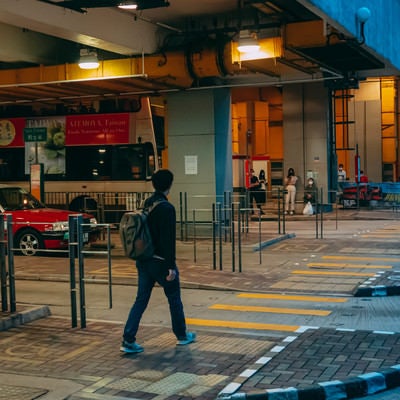 バス乗り場に向かうリュックサック香港男子の写真