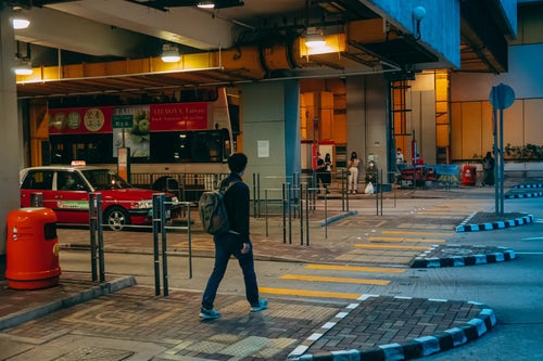 バス乗り場に向かうリュックサック香港男子の写真