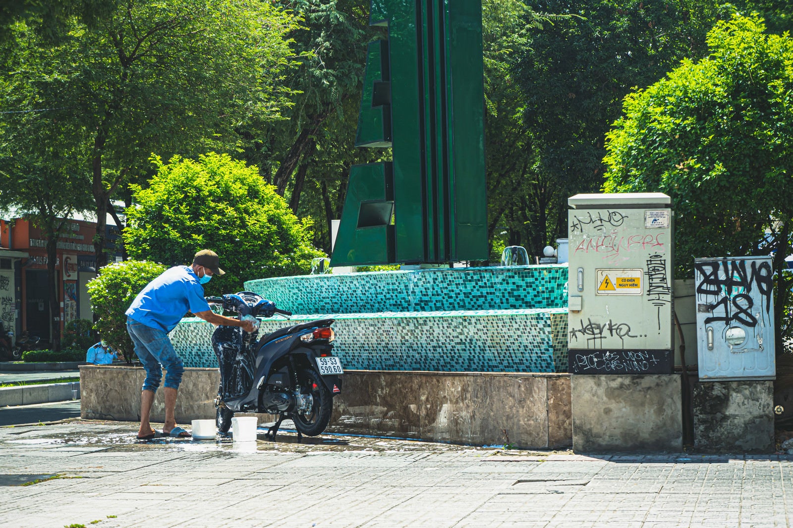 「噴水を利用してバイクを洗う東南アジアのライフハック」の写真