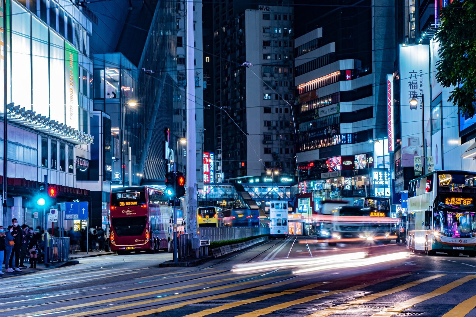 「【香港-銅鑼湾】信号待ちしている歩行者の前を走るバスや車」の写真