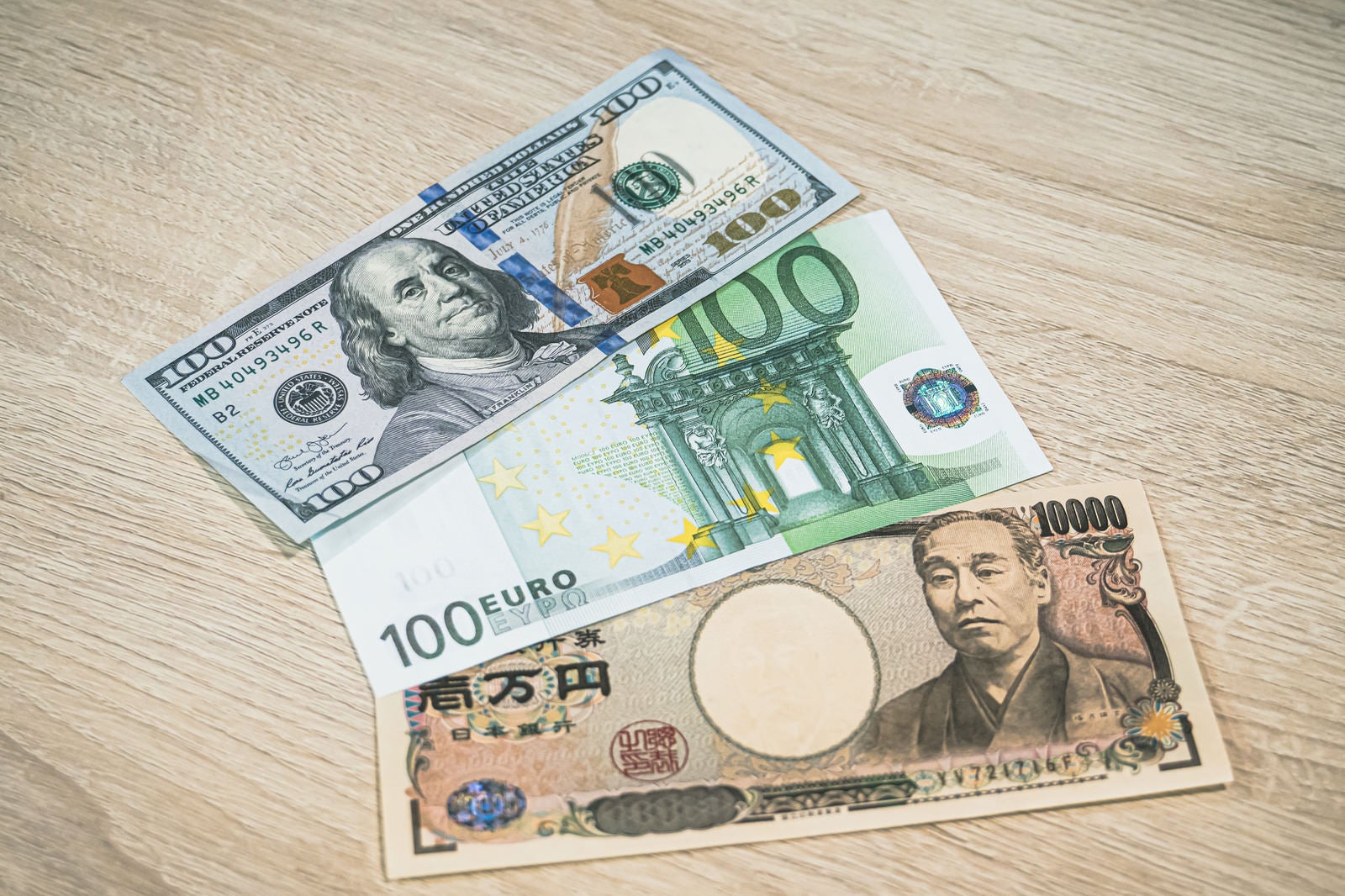 「100ドル、100ユーロ、1万円の紙幣」の写真