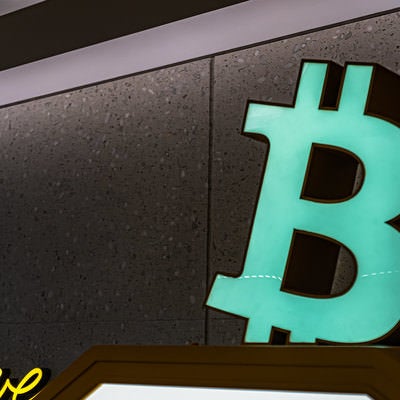 ビットコインのロゴが掲げられている仮想通貨自動販売機の写真