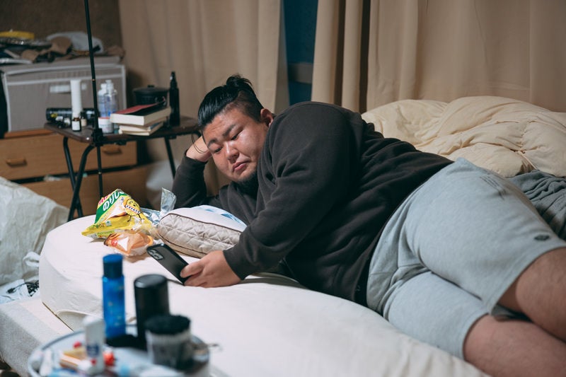 肘枕でスマホを眺めるぐうたら男性
