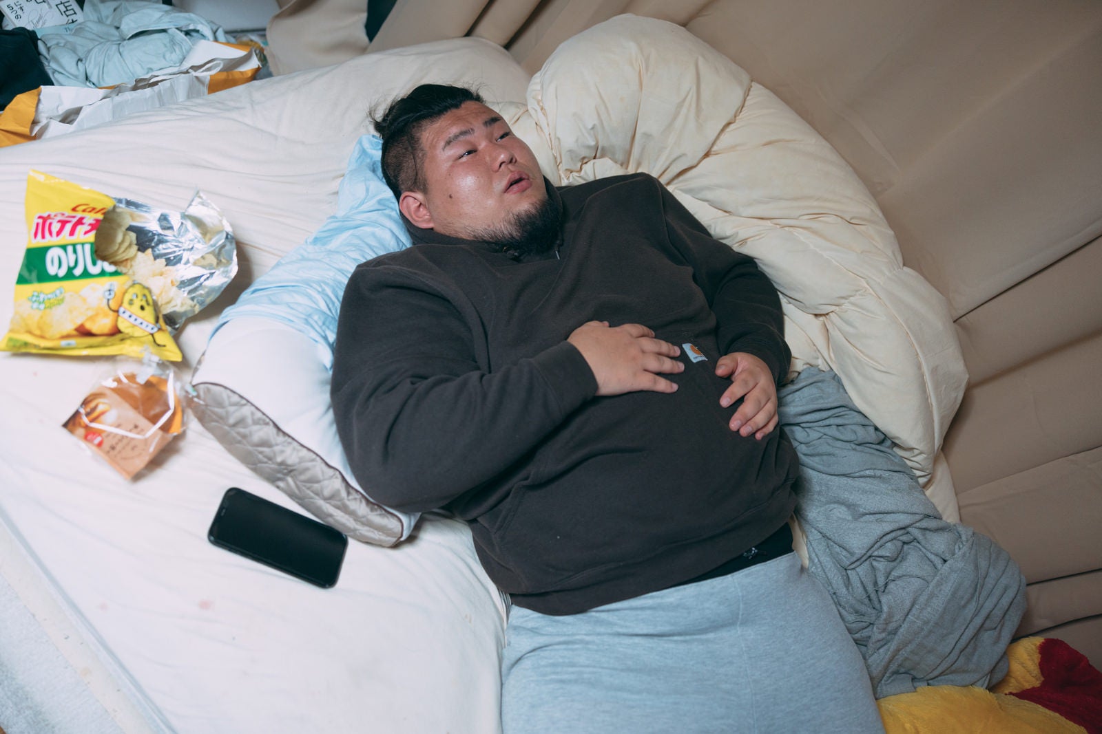 「食いすぎてベッドで横になるデブ」の写真［モデル：ノリックス］