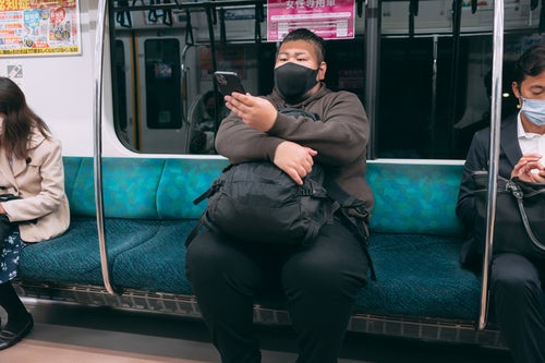 電車の席に座る160キロの男性の写真