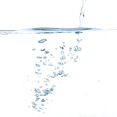 水面と注ぐ水の気泡の写真
