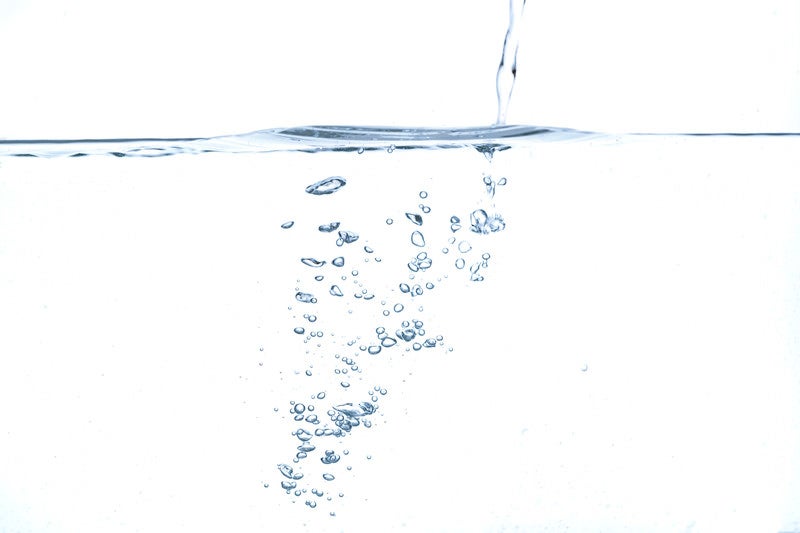 水面と注ぐ水の気泡の写真