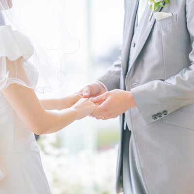 結婚式の指輪交換を終えて花嫁の手をもつ優しい新郎の手元の写真