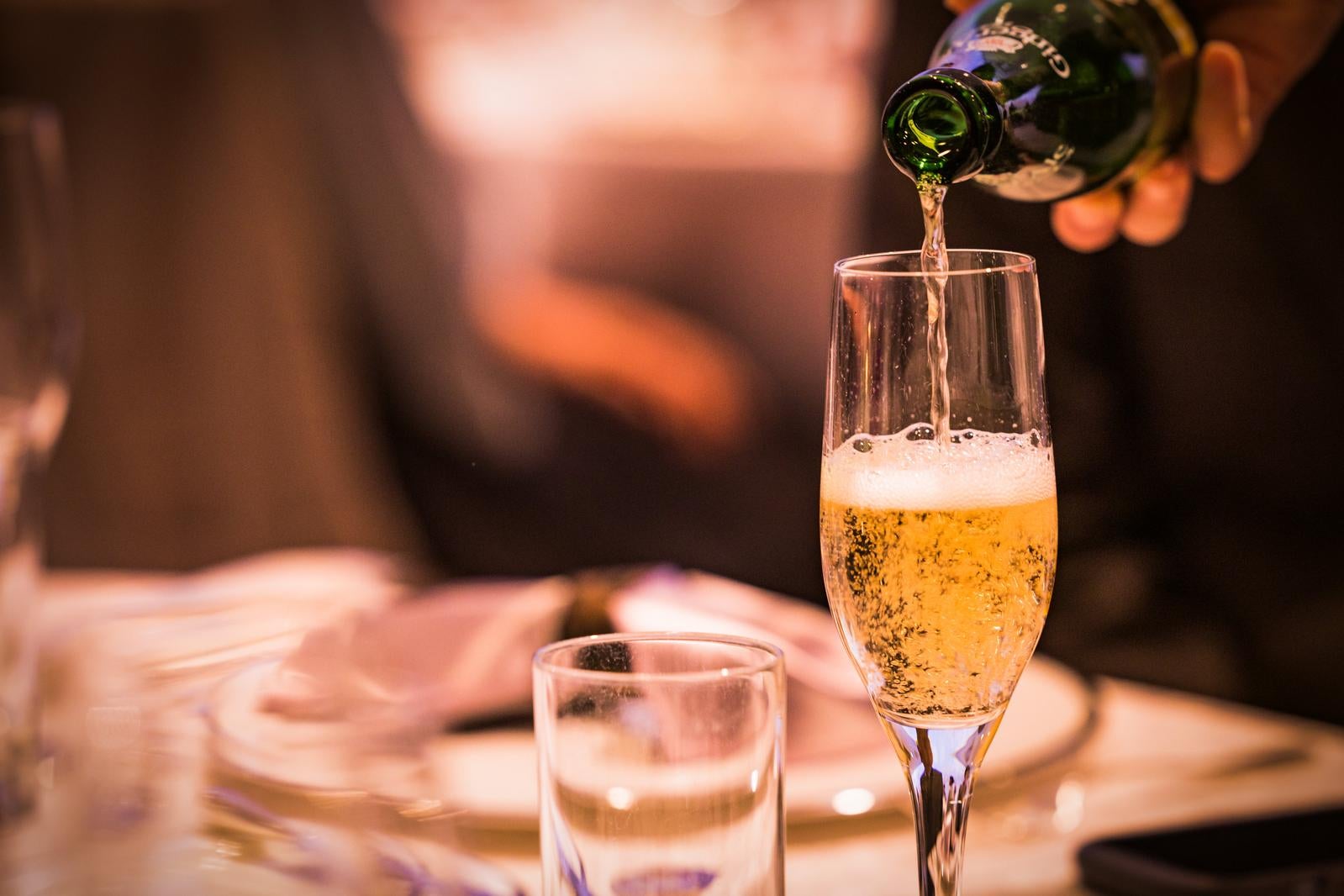 「宴会場でグラスにシャンパンをそそぐ様子」の写真