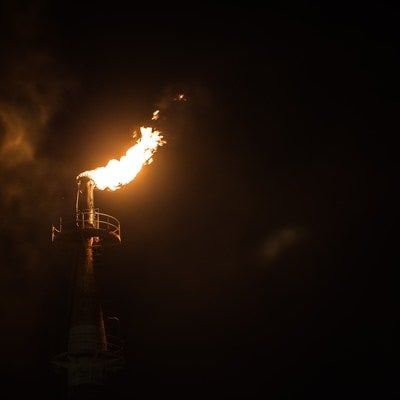 工場の煙突からあがる炎の写真