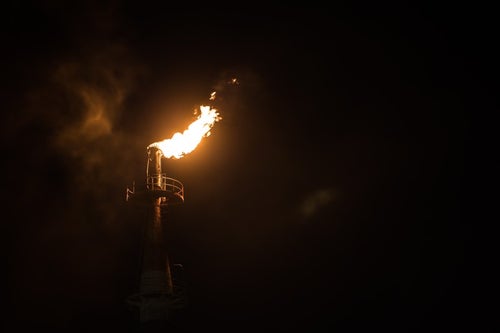 工場の煙突からあがる炎の写真