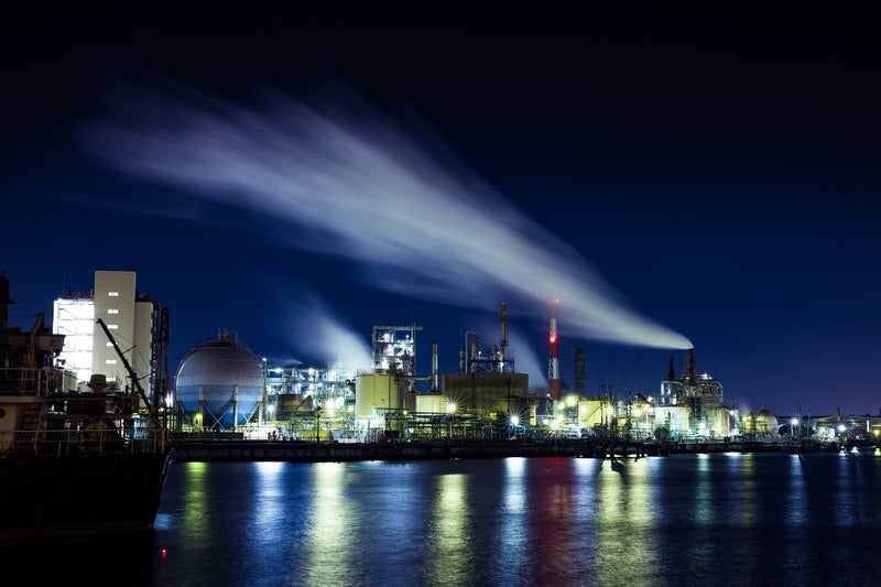 夜空に流れる排煙と工場夜景の写真