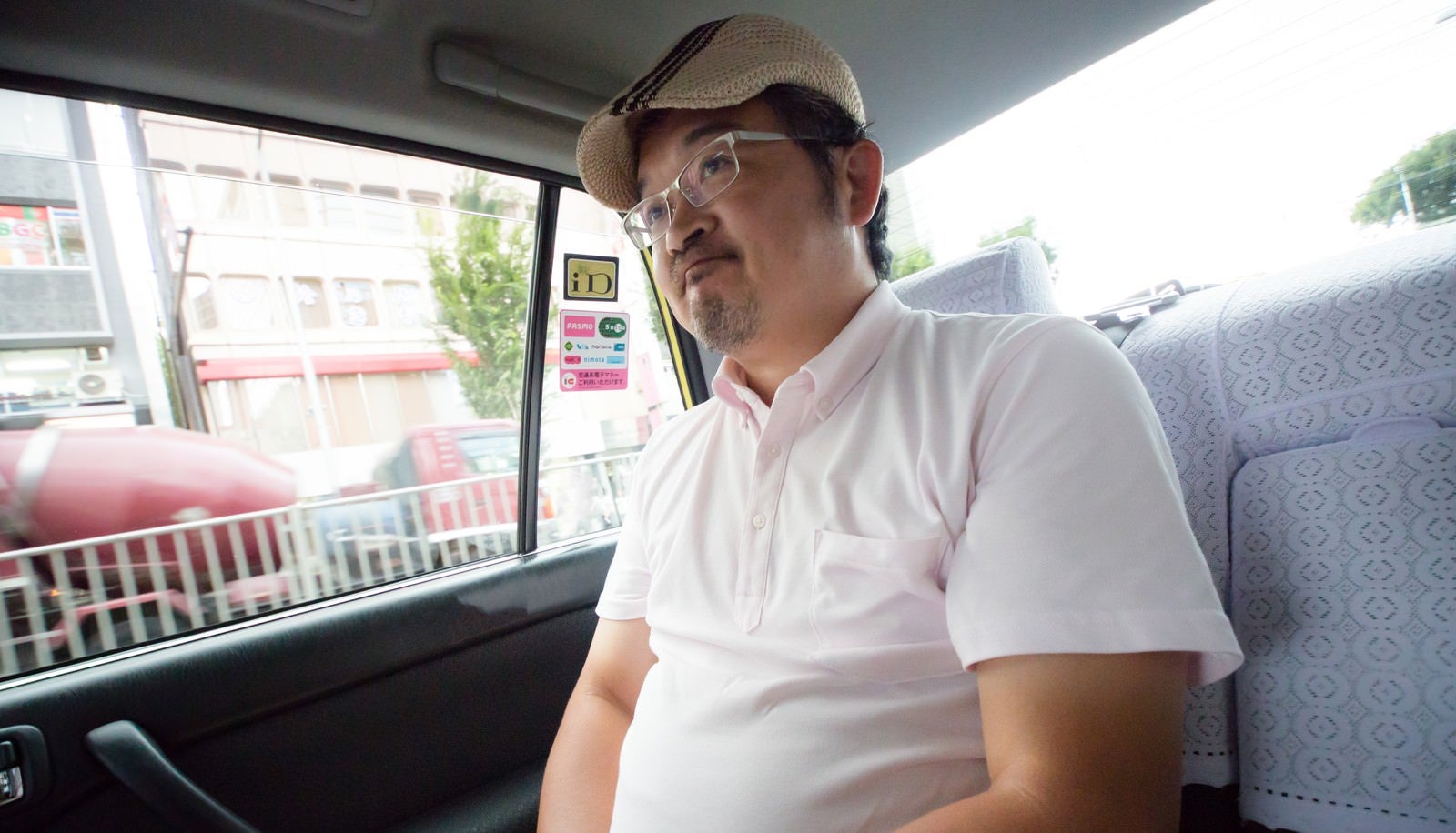 「タクシーの運転手に丸くなったと言われて苦笑いをするハンチング帽の男性」の写真［モデル：ナリシゲ］