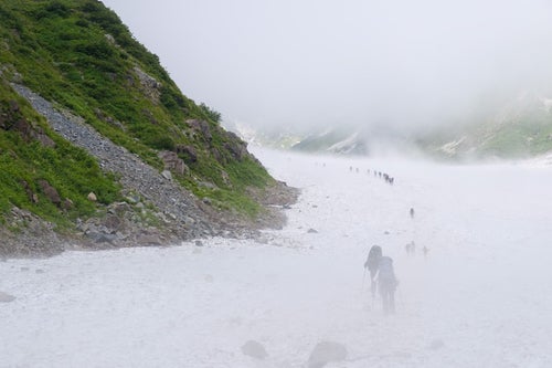 ホワイトアウトする白馬大雪渓に挑む登山者達（白馬岳）の写真