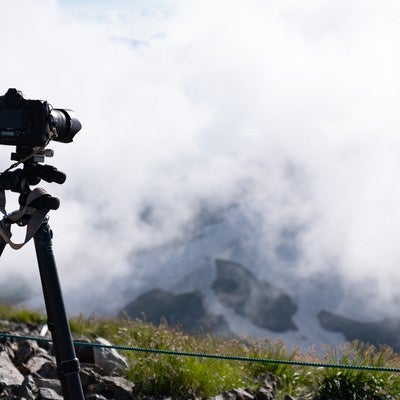 山頂で構える一眼レフカメラと三脚（白馬岳）の写真