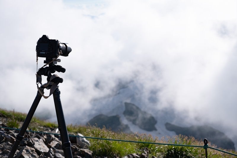 山頂で構える一眼レフカメラと三脚（白馬岳）の写真